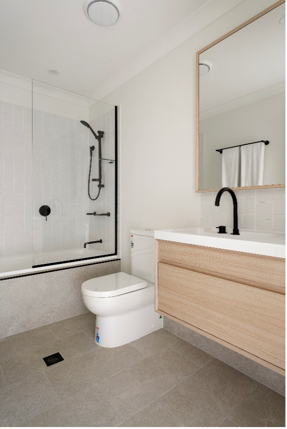 Munro by Azure bathroom one featuring BNK Modica back-to-wall toilet, Nero Mecca hob basin mixer, Nero Builder rail shower and Decina Bambino inset bath, all in matte black.